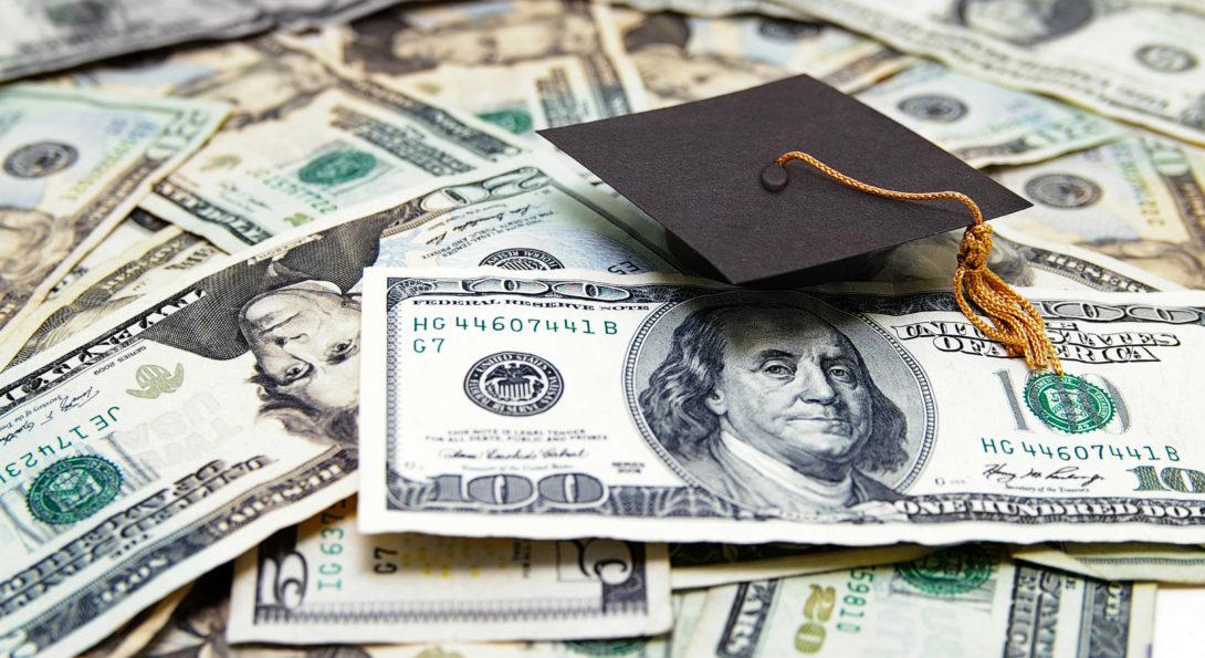 graduation cap atop dollar bills