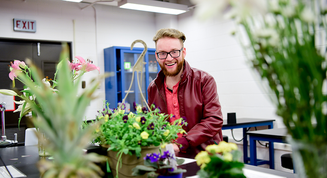 Student with plant specimens at a mircroscope