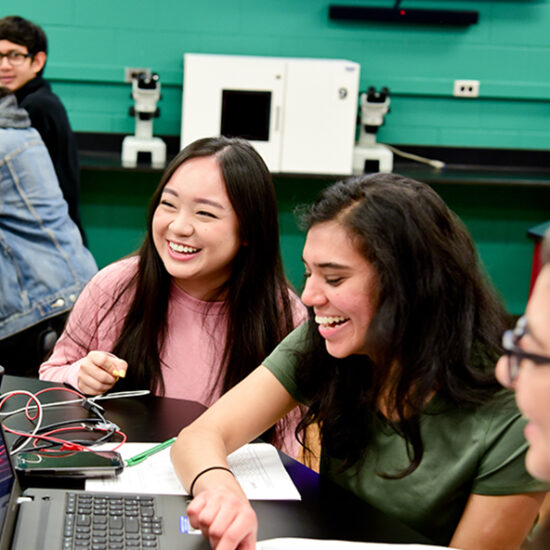 Female students smiling while coding