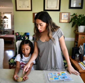 Linda Ortiz and her daughter, Sophie, prepare to play Lotería, a popular Spanish game. Sophie is part of a bilingual education class at UCLA Lab School, where she is learning 90% Spanish and 10% English. © Harrison Hill, USA TODAY 