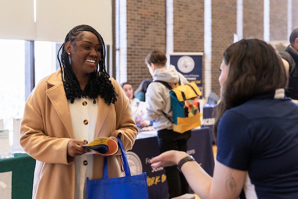 Young black female student smiles and socializes with employer at the spring career fair.