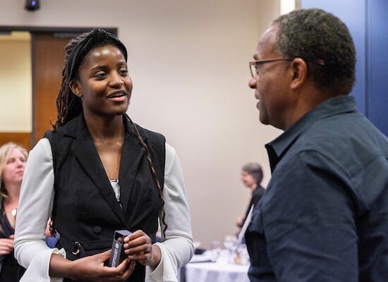 Young black female student speaking with adult male at scholarship luncheon for Liberal Arts and Sciences recipients.