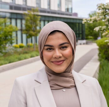 Young female student Nur stands in front of the Academic and Residential Complex on UIC's East Campus
                  