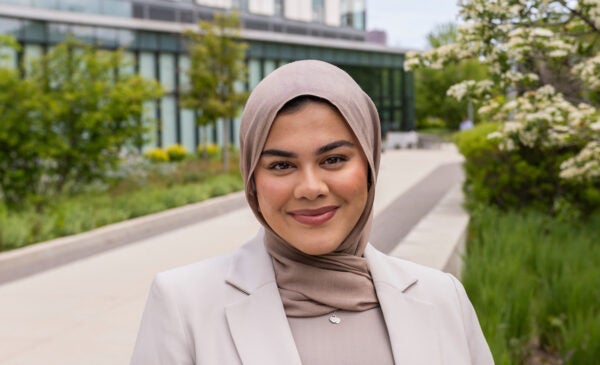 Young female student Nur stands in front of the Academic and Residential Complex on UIC's East Campus