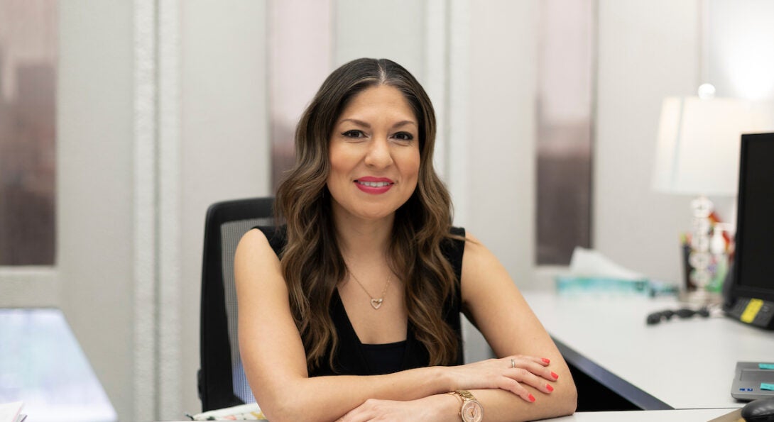 Director of Career Development and Internships Elizabeth Herrera sits in her office. She is a Latina woman with long brown wavy hair and a black sleeveless top.