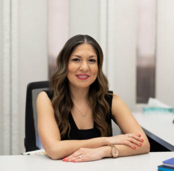 Director of Career Development and Internships Elizabeth Herrera sits in her office. She is a Latina woman with long brown wavy hair and a black sleeveless top.
                  