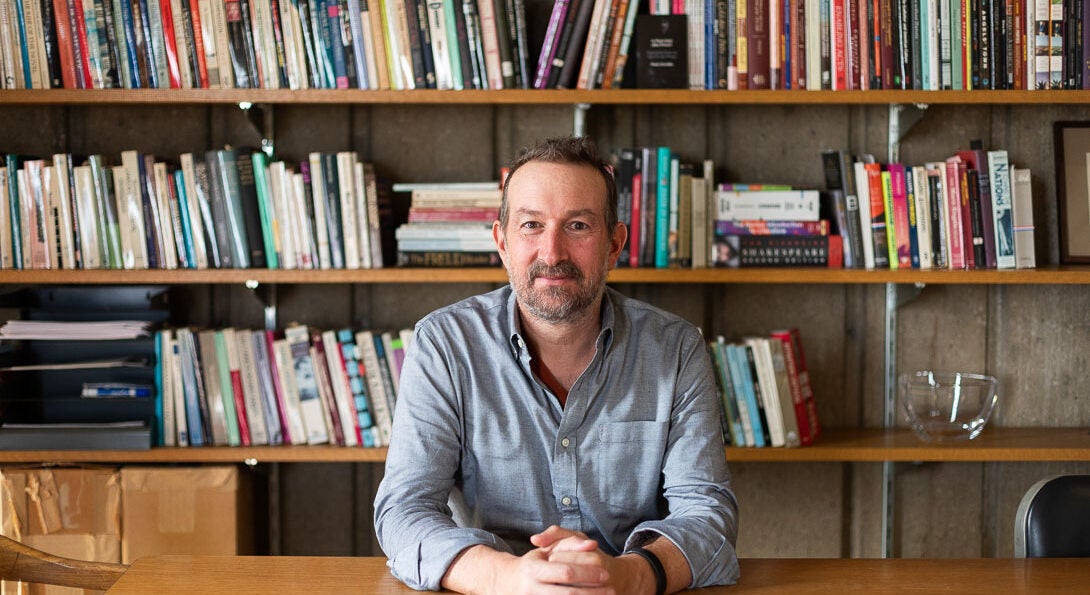 English Professor and Head of English Department Peter Coviello sits in front of his wall of books.