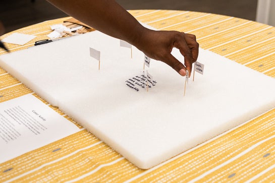 Hand reaches in to put a small flag into an art installation.