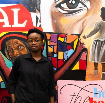 Venus Obazuaye stands in front of gallery wall at the Black Cultural Center
                  