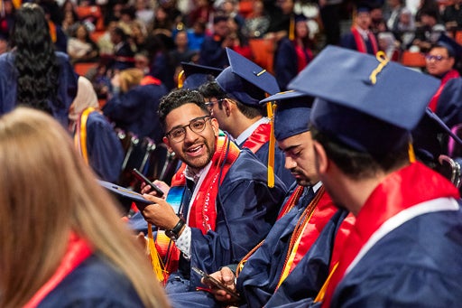 Student smiling next to classmates at commencement