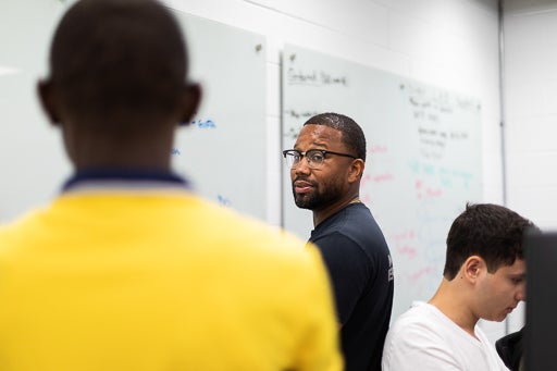 Faculty looks at student in front of white board while they solve a problem