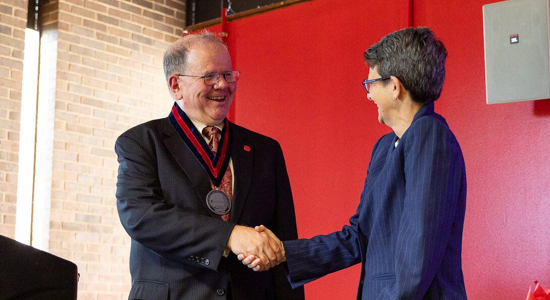 Distinguished Professor Donald Wink shakes LAS Dean Lisa A. Freeman's hand