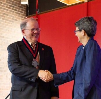 Distinguished Professor Donald Wink shakes LAS Dean Lisa A. Freeman's hand
                  