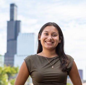 Student Jiselle Plata stands on UIC's campus with the Chicago skyline in the background
                  