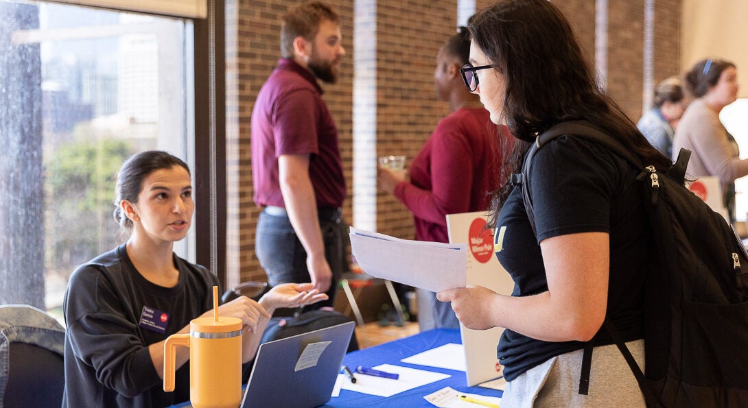 Integrated Health Studies advisor speaking with student at event