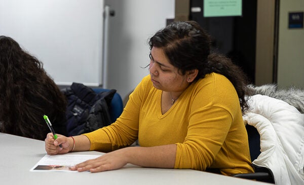 Student writing wearing a yellow shirt