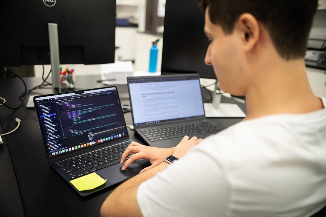 Student coding on computer in white t shirt