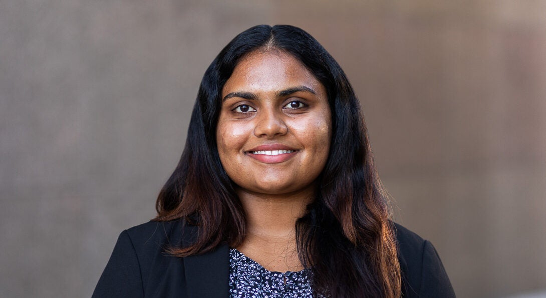 Student Ananya “Anna” Ramesh wearing a black blazer and floral shirt against brown background