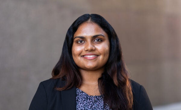 Student Ananya “Anna” Ramesh wearing a black blazer and floral shirt against brown background