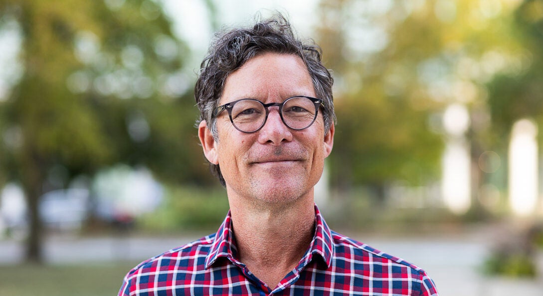 UIC Professor Christopher Grimes wearing checkerboard shirt stands on campus