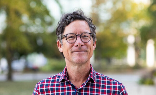 UIC Professor Christopher Grimes wearing checkerboard shirt stands on campus