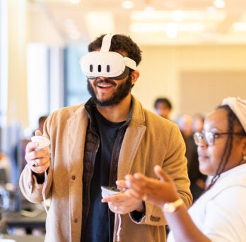 Students at AI Impact event wearing VR goggles and engaging with digital interface
                  