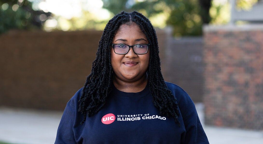 Student Kalya Pilgrim wearing glasses and blue crewneck sweatshirt on UIC's campus