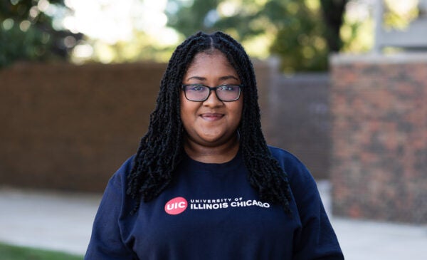 Student Kalya Pilgrim wearing glasses and blue crewneck sweatshirt on UIC's campus