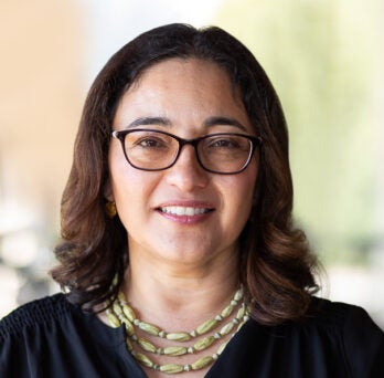 Lilia Fernandez has short brown hair, brown glasses and wears a black blouse
                  