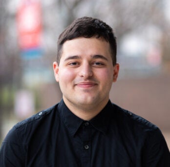 English student Liam Smith in black button down shirt on UIC's campus in the spring
                  