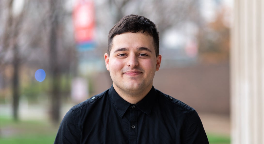 English student Liam Smith in black button down shirt on UIC's campus in the spring