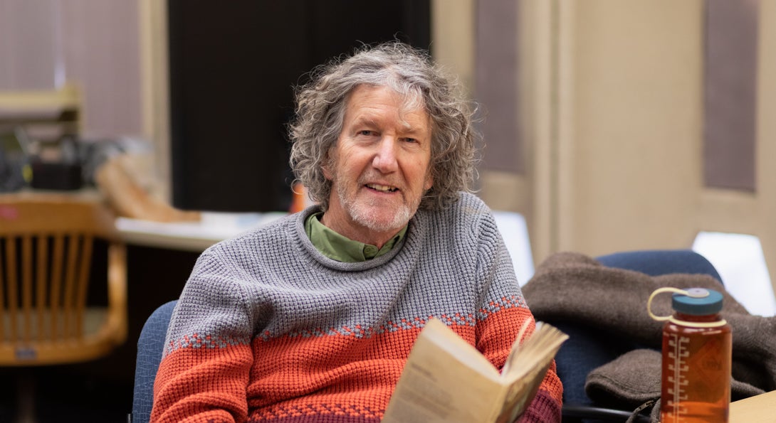 Professor Dave Schaafsma sits reading a book at a table in his office