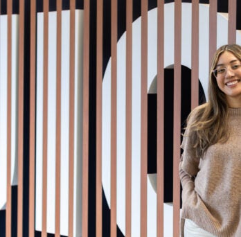 Alumna Naomi Martinez stands in front of UIC sign on campus
                  