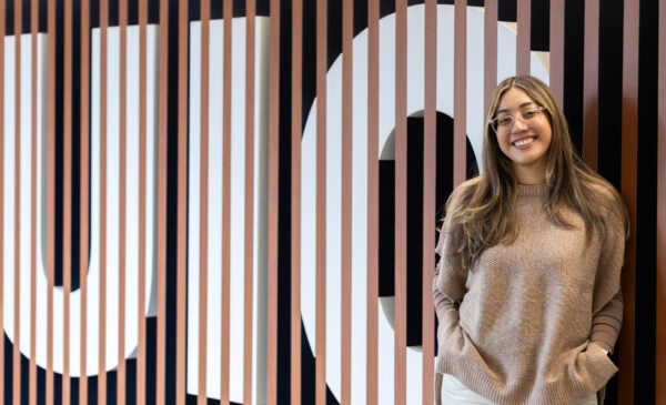 Alumna Naomi Martinez stands in front of UIC sign on campus