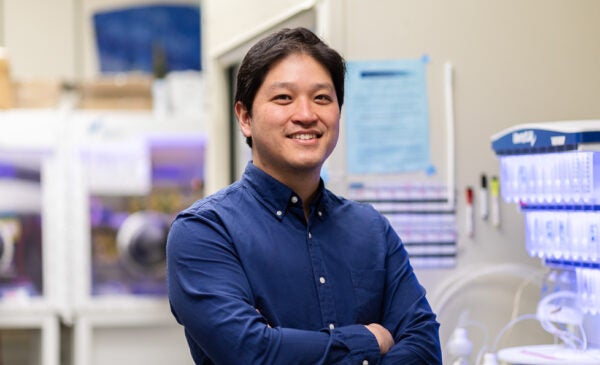 Professor Andy Nguyen in blue button down shirt standing in a lab