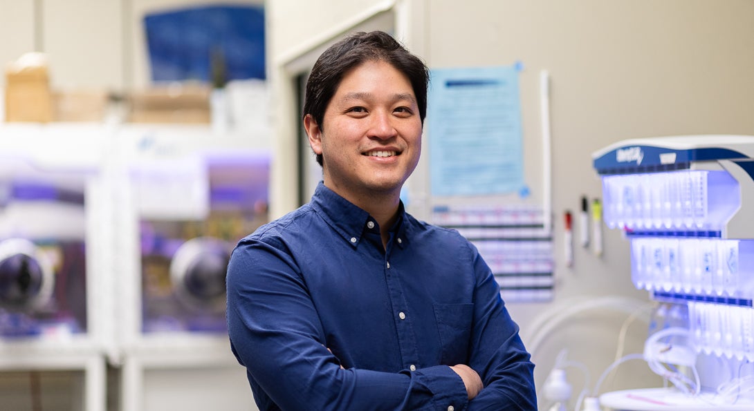 Professor Andy Nguyen in blue button down shirt standing in a lab