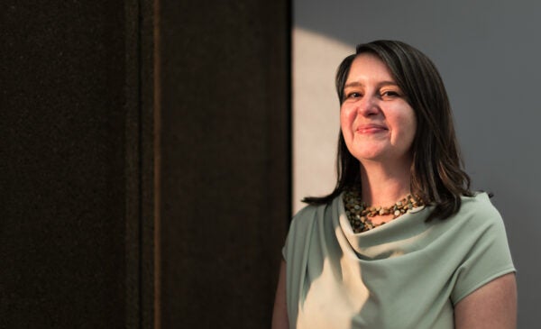 Anna Kornbluh stands in a dark room with sunlight falling onto half of her face