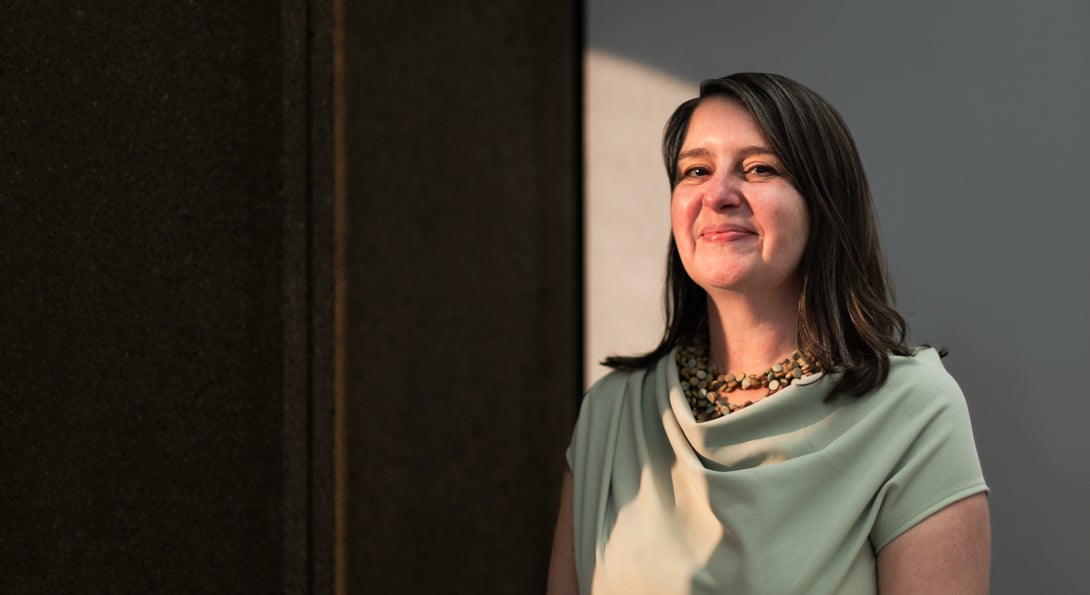 Anna Kornbluh stands in a dark room with sunlight falling onto half of her face