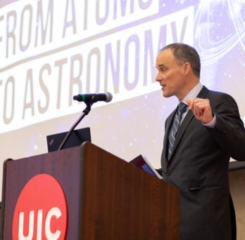 Robert Klie stands onstage at faculty research symposium at UIC
                  