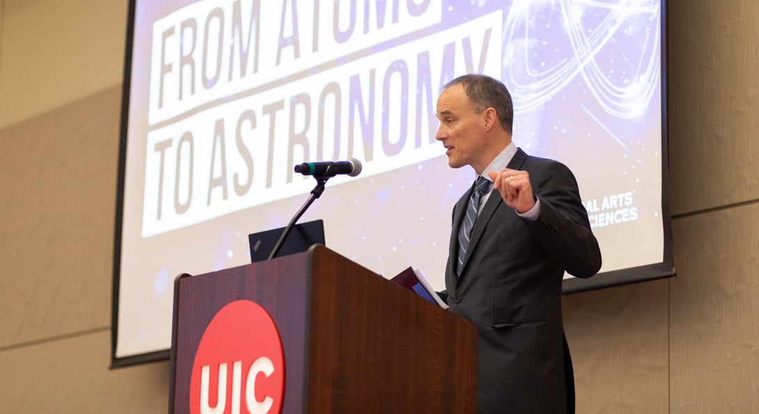 Robert Klie stands onstage at faculty research symposium at UIC