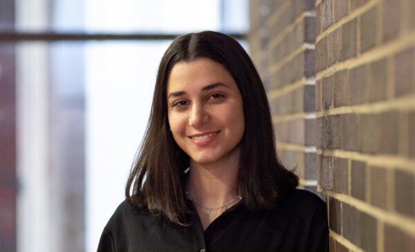 Student Kaya stands against brick wall in student center